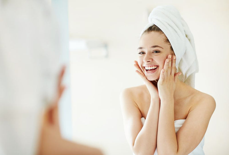 Smiling woman looking at her skin in a mirror
