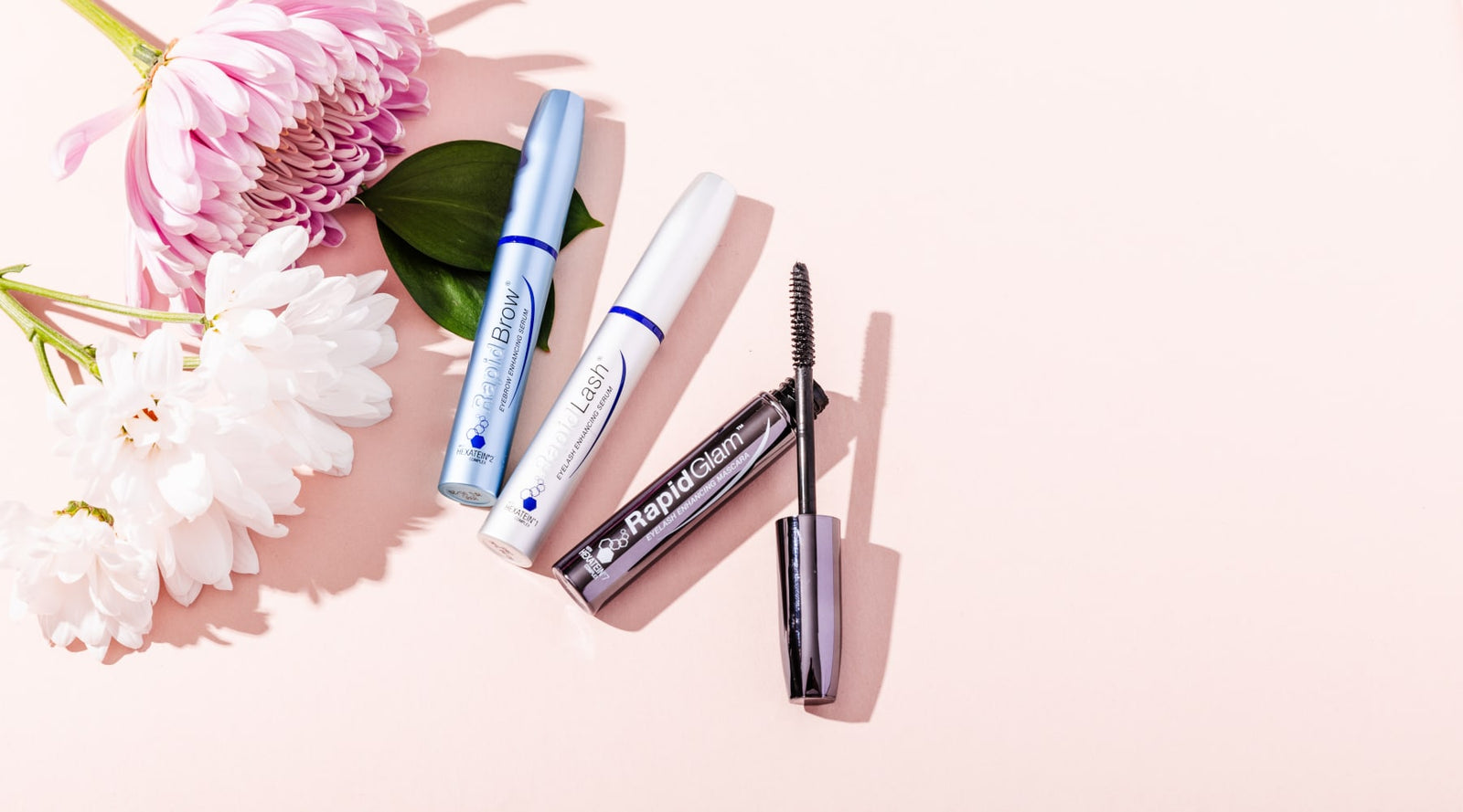 RapidBrow®, RapidLash®, and RapidGlam™ products on a pink background with flowers around it