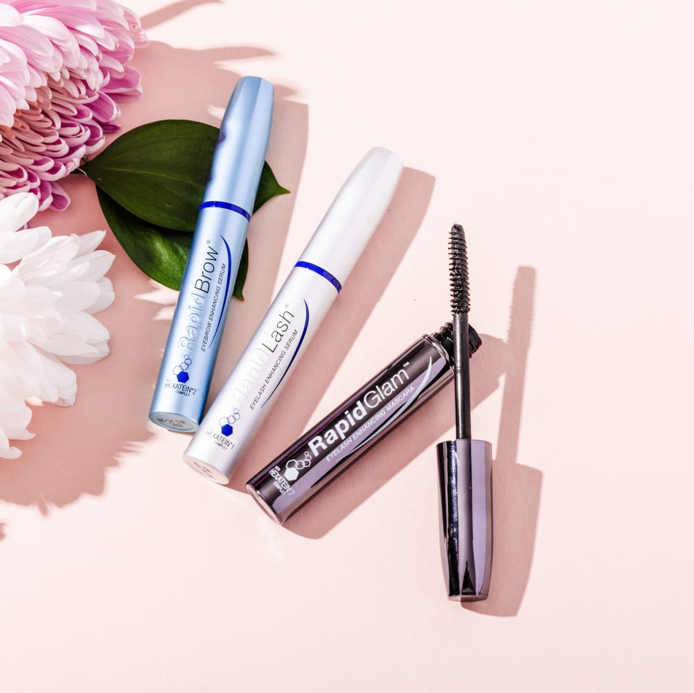 RapidBrow®, RapidLash®, and RapidGlam™ products on a pink background with flowers around it